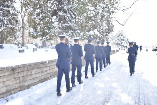 Group of people dressed in military walking along a pathway in the snow