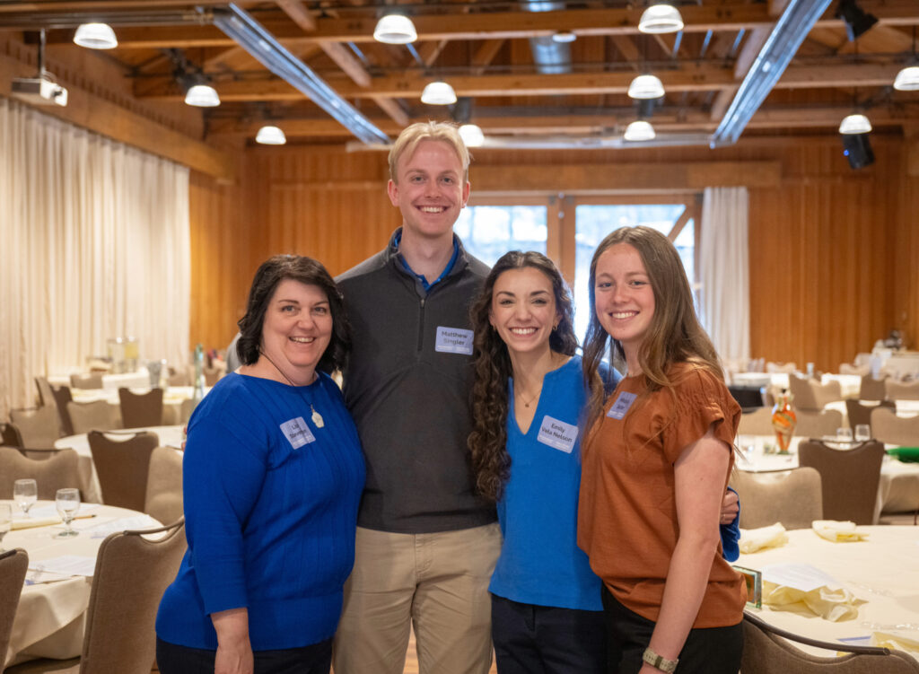 Four students pose for a photo together before the start of a conference.
