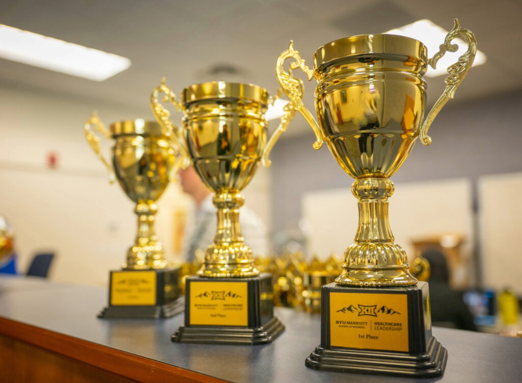 Golden trophies sit on a desk.