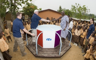 Ben Markham of Empower Playgrounds, Inc., greets the chief of Essam village as they celebrate the completion of an electricity-generating merry-go-round at the Golden Sunbeam School in Ghana