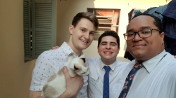 Sam Snell holding a cat while standing next to his two roommates