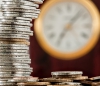 Stack of coins in front of blurred clock face