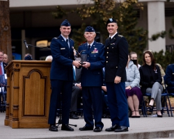 Air Force cadet Derek LeSueur and Army cadet Dillan Rowley present Hess with the Patriots Award. Photo courtesy of BYU Photo.