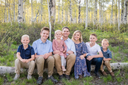 Ben Iverson, his wife, and their 5 kids sitting on a log in the forest