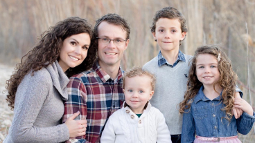 A family photo of Jess, her husband, and their three kids. The photo was taken outside.
