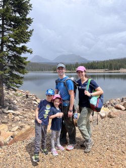 Jess, her husband, and their three kids standing in front of a lake, all with hats on