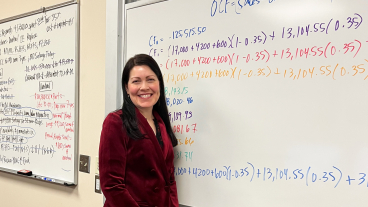 Photo of Jenn Larson in front of whiteboard with finance equations