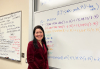 Photo of Jenn Larson in front of whiteboard with finance equations