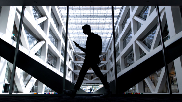 A student's silhouette mid-stride with the Tanner Building atrium in the background.