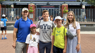 A family in front of the U.S. Open stadium with a wife, husband and three children.