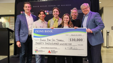 Group of people in business casual attire pose for photo with oversized check for $30,000.