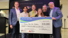 Group of people in business casual attire pose for photo with oversized check for $30,000.