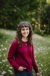 A woman in a red sweater stands in a field of flowers