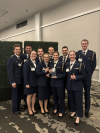 Ten AFROTC cadets stand in their formal attire as Anaiya Harris holds the heritage award.