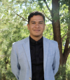 Finance senior Emilio Barrios Ramos poses for a professional photo, dressed in a business suit and standing in front of a tree.