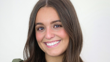 Ellie Draper smiles in a headshot wearing a dark green blouse.