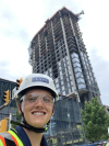 Smith smiles with his hard hat on and standing in front of a building under construction.