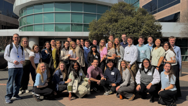 Students crowd together in front of a building for a group photo.