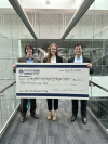 Three professionally-dressed students hold a giant check worth $3,000 as their prize for winning the Computers for Change case competition.